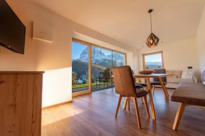 a living room with a dining room table with a view at Luech da Perteut - Panorama and Wellness in Santa Cristina in Val Gardena