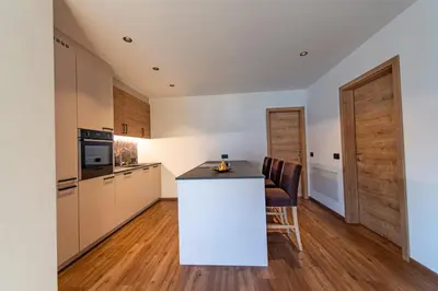 a kitchen with a white island in a room at Luech da Perteut - Panorama and Wellness in Santa Cristina in Val Gardena