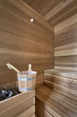 a wooden sauna with a bucket in it at Floris Green Suites by Parc Hotel Florian in Siusi