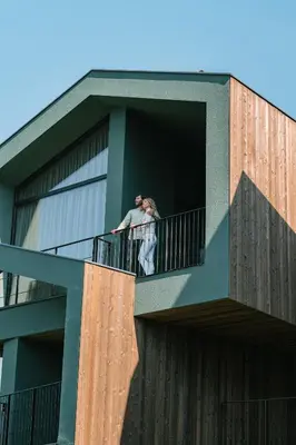 two people standing on a balcony of a building at Floris Green Suites by Parc Hotel Florian in Siusi