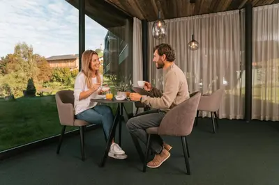 a man and woman sitting at a table on a patio at Floris Green Suites by Parc Hotel Florian in Siusi