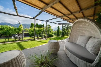 a porch with a wicker chair and a table at Hotel Frangart an der Weinstraße in Appiano sulla Strada del Vino