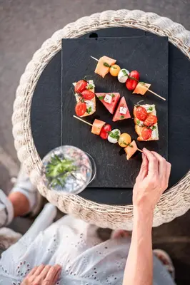 a person holding a plate of food on a table at Hotel Frangart an der Weinstraße in Appiano sulla Strada del Vino