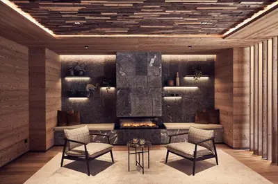 a living room with a fireplace and chairs at Falkensteiner Hotel Kronplatz - The Leading Hotels of the World in Brunico