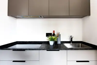 a kitchen with white cabinets and a sink at Casteller Apartment Deluxe in La Villa