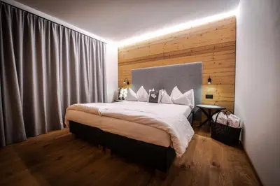 a bedroom with a large bed with a wooden wall at Casteller Apartment Deluxe in La Villa
