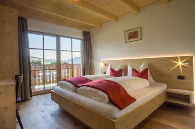 a bedroom with a large bed with a large window at Holzerhof in Valdaora di Sotto