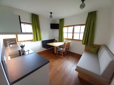 a living room with a kitchen and a table at Holzerhof in Valdaora di Sotto