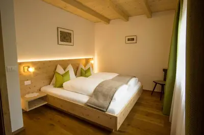 a bedroom with a white bed with green pillows at Holzerhof in Valdaora di Sotto