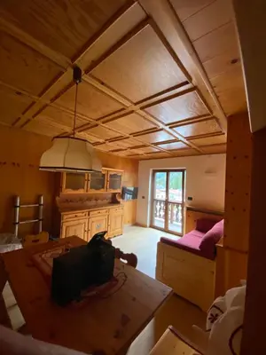 a living room with a wooden ceiling and a table at Casa Doleda in Alba di Canazei