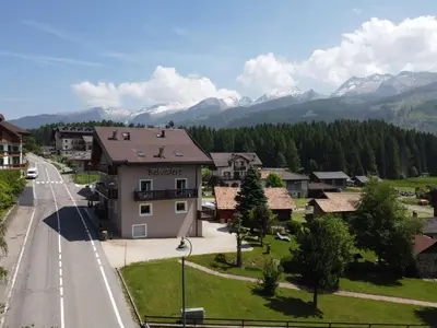 a town with mountains in the background and a street at Garnì Belvedere in Predazzo