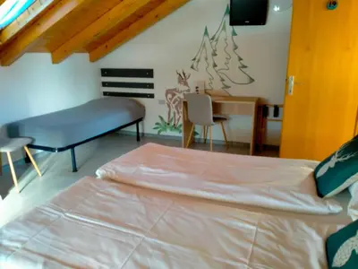 a bedroom with a bed and a desk and a chair at Garnì Belvedere in Predazzo