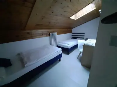 a room with two beds and a desk and a window at Garnì Belvedere in Predazzo