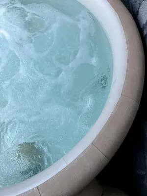 a bath tub filled with blue water in a bath room at Garnì Belvedere in Predazzo