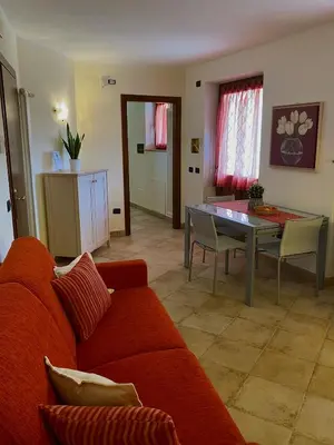 a living room with a red couch and a table at Appartamento Le Colonne - Relais Villa Quercia in Tassullo