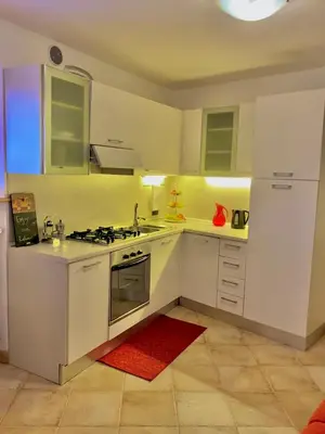 a kitchen with white appliances and a red rug at Appartamento Le Colonne - Relais Villa Quercia in Tassullo