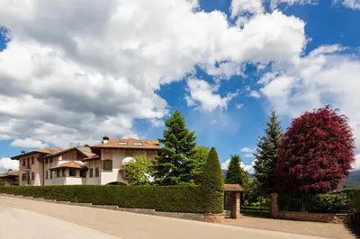 a house on a street with bushes and trees at Appartamento Le Colonne - Relais Villa Quercia in Tassullo