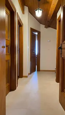 an empty hallway with wooden doors and tile floors at Attico Vista Tofane in Cortina dʼAmpezzo