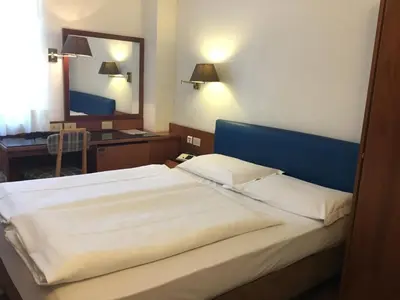 a bedroom with a large bed and a mirror at Hotel Adria in Bolzano