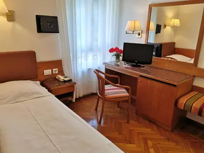 a hotel room with a bed and a desk with a television at Hotel Adria in Bolzano