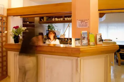 a woman standing behind a counter in a store at Hotel Adria in Bolzano