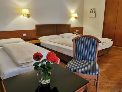 a hotel room with a bed and a table with a vase of flowers at Hotel Adria in Bolzano