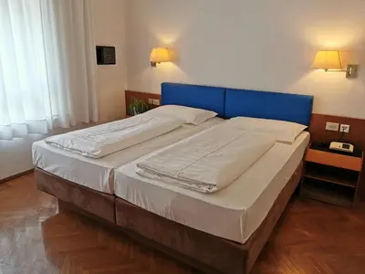 a large bed with a blue headboard in a bedroom at Hotel Adria in Bolzano