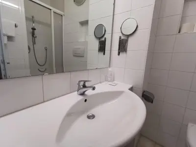 a white bathroom with a sink and a mirror at Hotel Adria in Bolzano