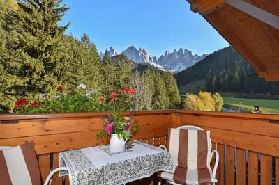 a table and chairs on a balcony with a view at Hotel Ranuimüllerhof in Villnoss