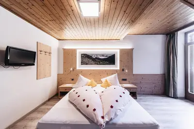 a bedroom with a bed with a tv on the wall at Hotel Ranuimüllerhof in Villnoss