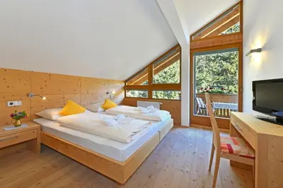 a bedroom with a bed and a desk and a television at Hotel Ranuimüllerhof in Villnoss
