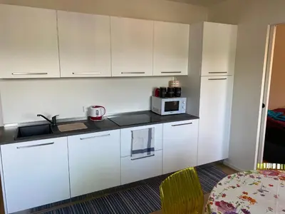 a kitchen with white cabinets and a microwave at Casa sciliar blu centro paese in Fiè