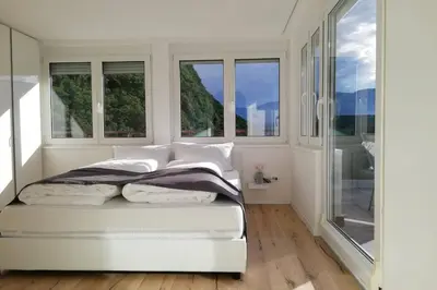 a white bedroom with windows and a bed at Apartment Mathilda in Bolzano
