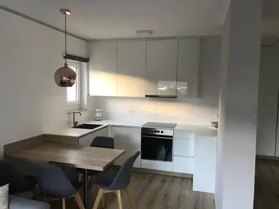 a kitchen with white cabinets and a wooden table and chairs at Apartment Mathilda in Bolzano