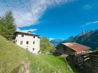 a building on the side of a grassy hill at Casa Soraya in Falcade