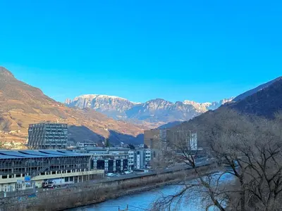 a city with a river and mountains in the background at Bozen - voll ausgestattet, optimale Lage in Bolzano