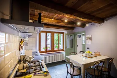 a kitchen with a stove and a table with chairs at LA PITA AGORDINA in Cancellade