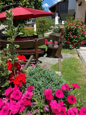 a garden with flowers and a bench and an umbrella at Villa Tisot in Fiera di Primiero