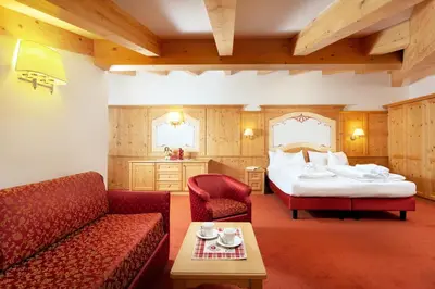 a hotel room with a bed and a couch and a table at Hotel Gries in Canazei