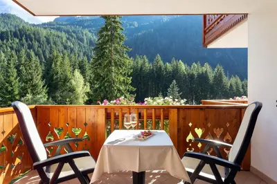 a table and chairs on a balcony with a view at Hotel Gries in Canazei