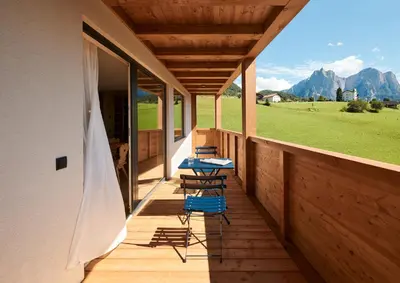 two chairs and a table on the porch of a house at Alpe di Susi in Castelrotto