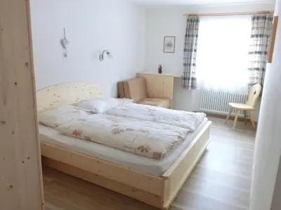 a bedroom with a bed and a chair and a window at Apartments Sotbosch in La Villa
