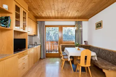 a kitchen and dining room with a table and chairs at Apartments Puntin in San Cassiano