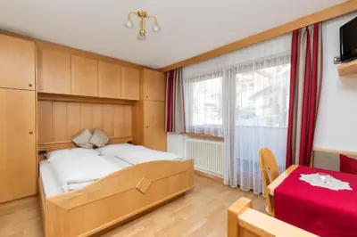 a bedroom with a large bed and a window at Apartments Puntin in San Cassiano