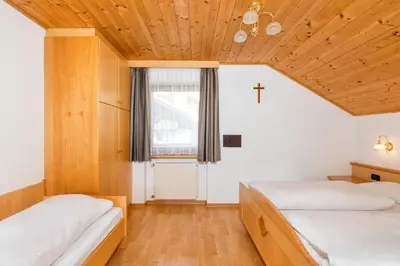 two beds in a room with a cross on the wall at Apartments Puntin in San Cassiano