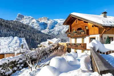 a wooden house in the mountains covered in snow at Ciasa Odlana in San Cassiano