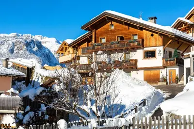 a wooden house in the snow with a fence at Ciasa Odlana in San Cassiano