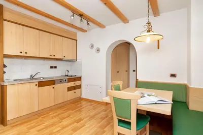 a kitchen with wooden cabinets and a wooden table and chairs at Ciasa Odlana in San Cassiano