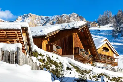 a log cabin with snow on the roof at Ciasa Odlana in San Cassiano