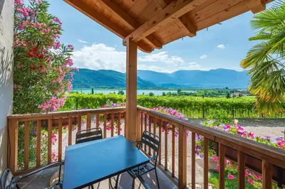 a porch with a blue table and chairs and flowers at Weinhof am See in Caldaro